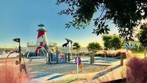 A park with a lighthouse, playground equipment, and a signpost.