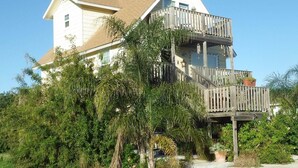 A two-story house with a wooden deck and a fenced backyard. - Island Serenity- Island Time Up in Old Town  (Port Aransas)