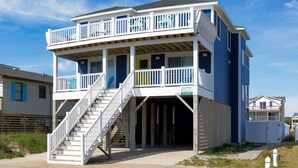 A two-story beachfront house with a balcony, a staircase leading to the upper level, and a visible address sign. - 4759- Sun Daze - Ocean Views, Pool, Hot Tub & Steps to Beach (Kitty Hawk)