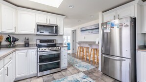 A modern kitchen with white cabinets, stainless steel appliances, a skylight, and a bar area. - 4759- Sun Daze - Ocean Views, Pool, Hot Tub & Steps to Beach (Kitty Hawk)