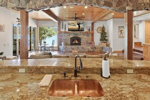 Una cocina con encimera de piedra, doble lavamanos y chimenea.