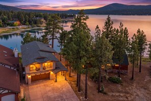 A residential property with a large house featuring a garage, a driveway, and a view of a lake and mountains.