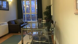 Un soggiorno moderno con tavolo da pranzo in vetro, divano in pelle e un'ampia finestra con tende.