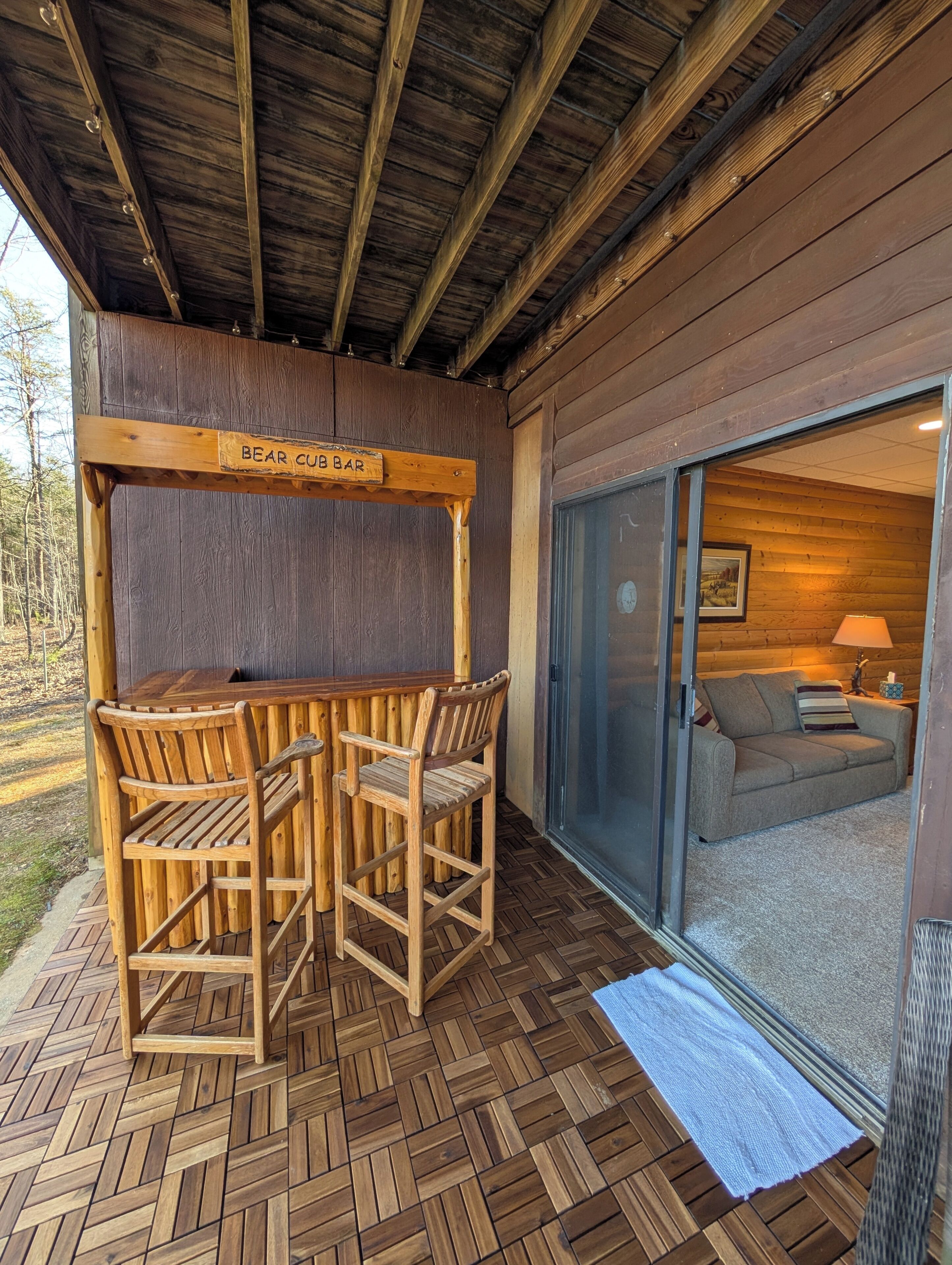 Un espace extérieur aménagé avec des sièges en bois, sur lequel est apposée une enseigne indiquant « BAR À OURSONS ».