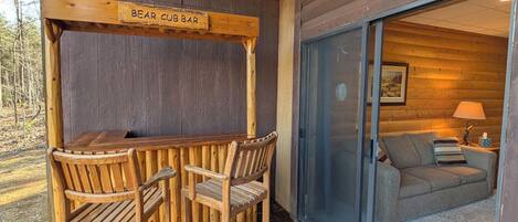Un espace extérieur aménagé avec des sièges en bois, sur lequel est apposée une enseigne indiquant « BAR À OURSONS ».