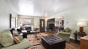 A spacious living room with a fireplace, a dining area, and a kitchen in the background. - Family Home in Town, Across from Rio Grande Trail (Glenwood Springs)