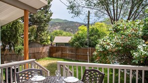 An outdoor patio with a table set for two, surrounded by a wooden fence and greenery. - Family Home in Town, Across from Rio Grande Trail (Glenwood Springs)
