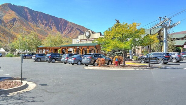 A parking lot with cars, a building with a clock, and mountains in the background. - Family Home in Town, Across from Rio Grande Trail (Glenwood Springs)