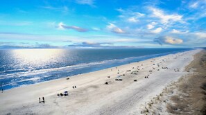 Une vaste plage où l’on peut voir des gens se prélasser au soleil et se promener le long du rivage.
