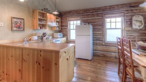 Eine Küche mit Holzausstattung, einem Kühlschrank, einer Mikrowelle und einem Spülbecken.