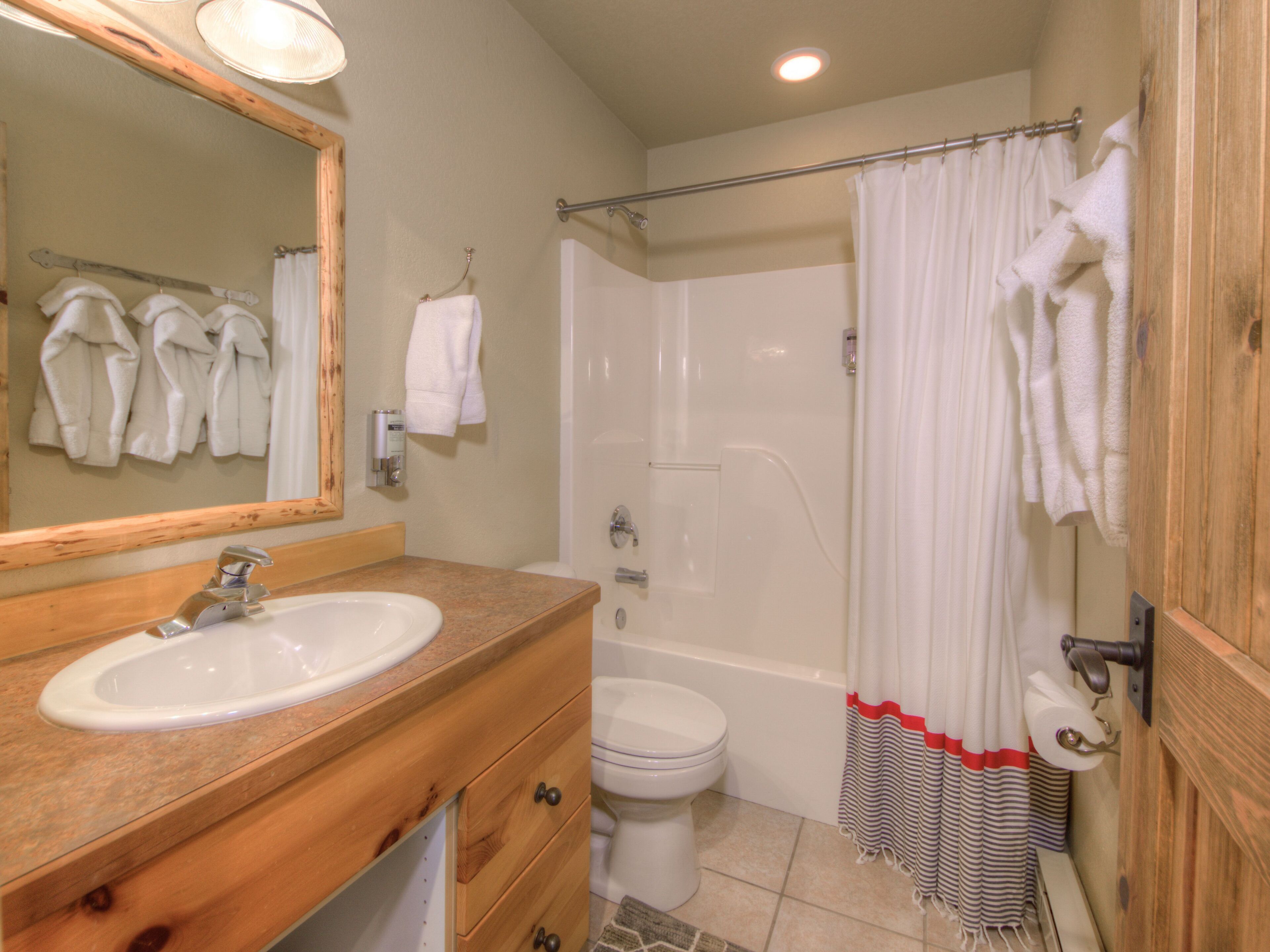 A bathroom with a wooden vanity, a sink, a toilet, and a shower area.
