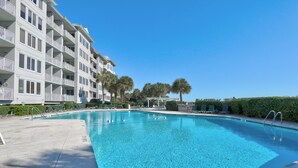 A rectangular swimming pool with clear blue water, surrounded by a concrete deck. There are lounge chairs and a small gazebo in the background. - Stunning Ocean Views from this Beautiful Condo with Pool, On-Site Amenities! (Hilton Head)