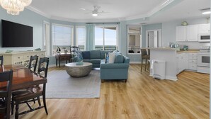 A spacious living room with a large sofa, a dining table, and a kitchen area. - Stunning Ocean Views from this Beautiful Condo with Pool, On-Site Amenities! (Hilton Head)