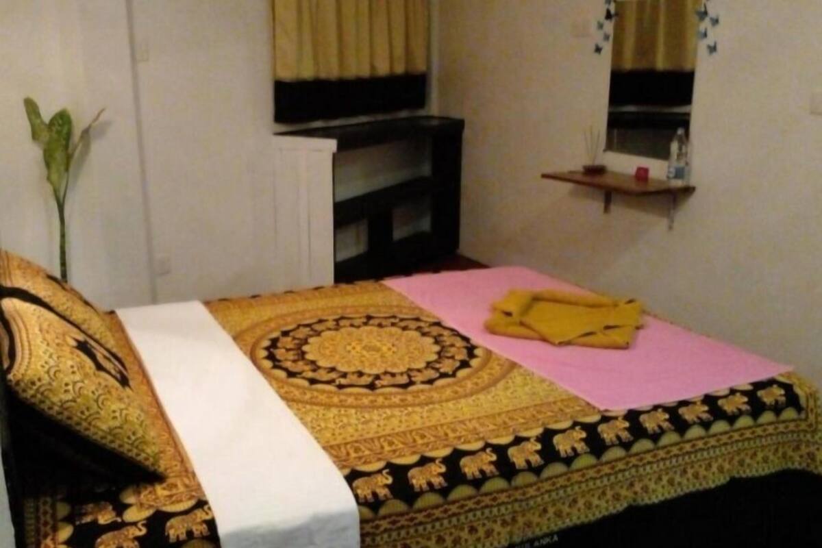 Ein Zimmer mit einem Bett, einem Nachttisch, einem Spiegel und einer kleinen Ablage.