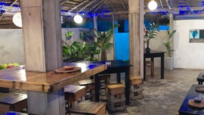 A rustic interior with wooden furniture, tables, and chairs arranged in a casual setting. - Malika's Yellow House (Hikkaduwa)