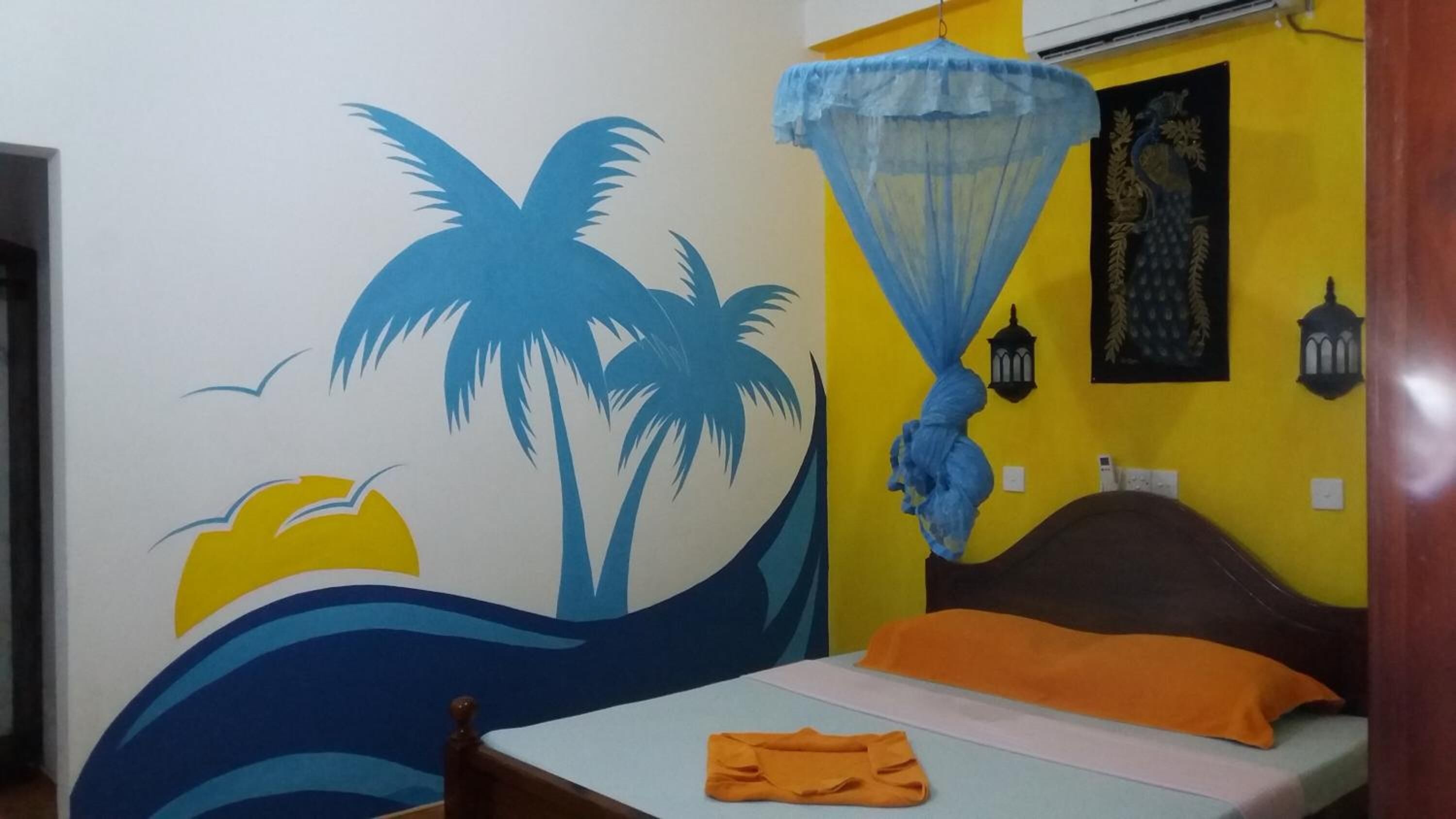 A room with a bed, a wall mural, a mosquito net, and a bedspread.