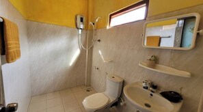 Bathroom features a toilet, sink, and shower area, with a towel rack and shelf for storage.