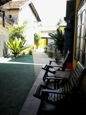 Guests can sit on benches facing the building with a tiled roof and window.