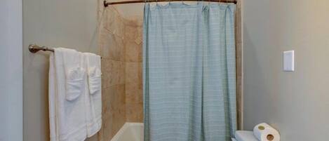 A bathroom with a shower curtain, a bathtub, and a toilet.