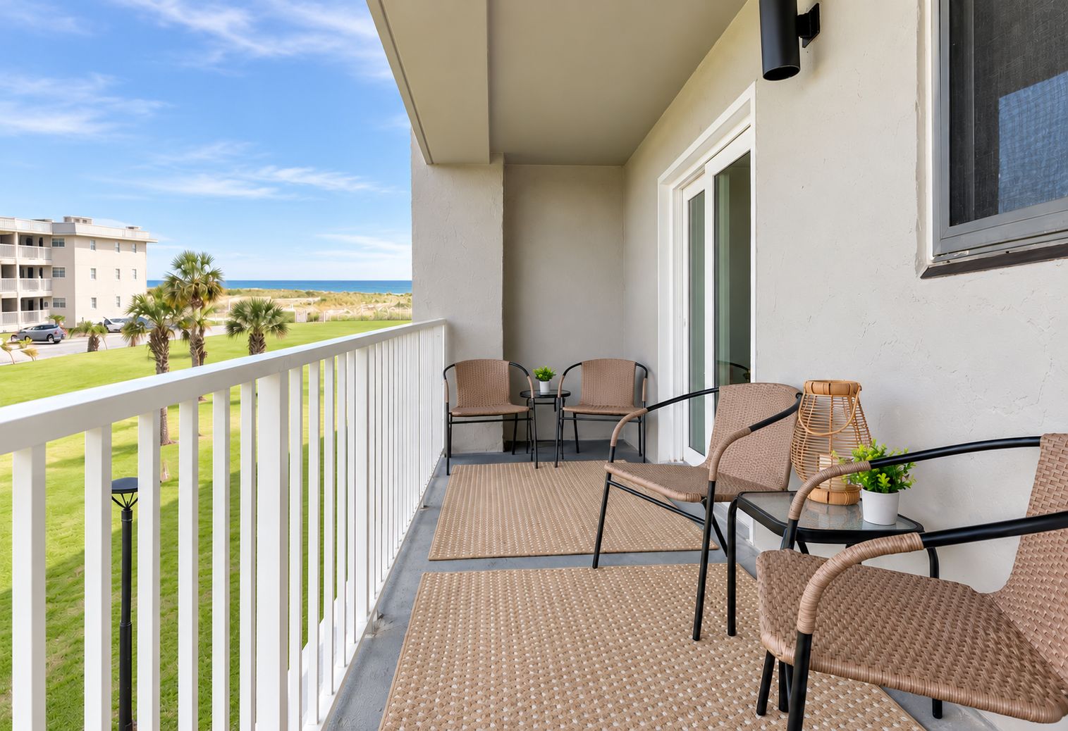 A balcony with wicker chairs, a small table, and a potted plant.