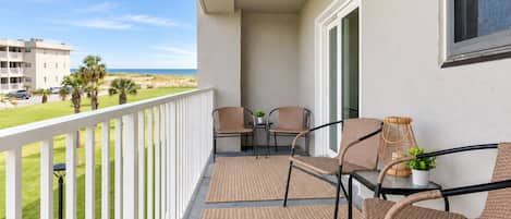 A balcony with wicker chairs, a small table, and a potted plant.