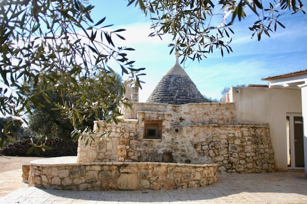 Stunning chapel with a conical roof, set amidst a serene courtyard and stone bench.