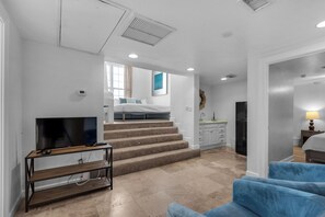 Stylish living area with a staircase, flat-screen TV, and comfortable sofa.