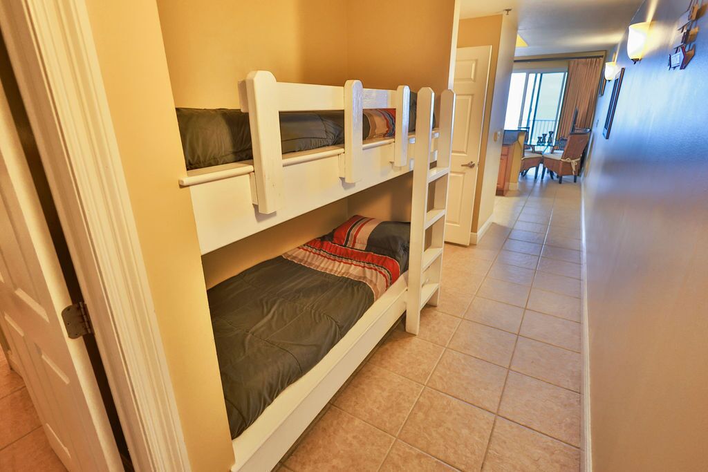 A hotel room with bunk beds, a dining area with chairs, and a view of the outside.