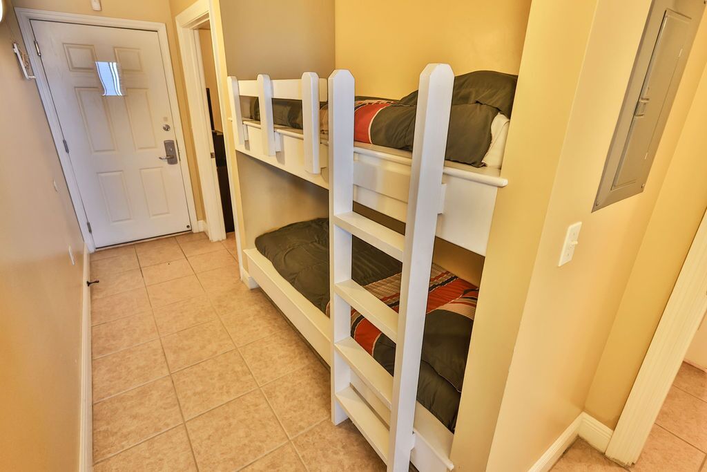 A room with bunk beds, a door, and a tiled floor.