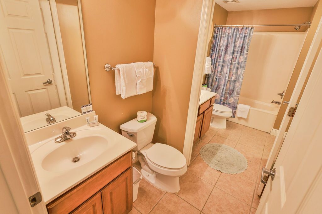 A bathroom with a sink, toilet, and shower curtain.