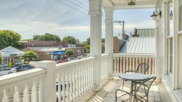 A balcony with a white railing, a table, and chairs.
