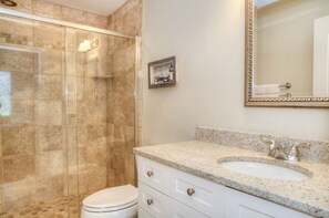Ein Badezimmer mit Dusche, Toilette, Waschbecken und einem gerahmten Bild an der Wand.