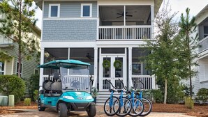 A two-story building with a balcony, a golf cart, and bicycles parked in front. - 2 King Suites, 2 Resort Pools, Golf Cart & 6 Bikes! Nature Trail to the Beach! ~ Go Coastal at NatureWalk on 30A (Santa Rosa Beach)