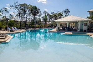 A pool area with lounge chairs and a covered seating area.
