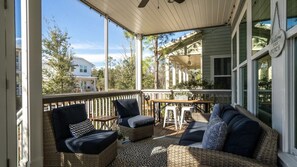 A covered porch with wicker furniture, a table, and chairs.