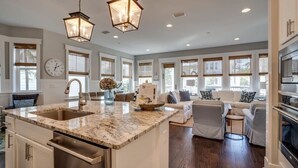 A spacious kitchen with a large island, modern appliances, and a dining area with a sofa and chairs. - 2 King Suites, 2 Resort Pools, Golf Cart & 6 Bikes! Nature Trail to the Beach! ~ Go Coastal at NatureWalk on 30A (Santa Rosa Beach)