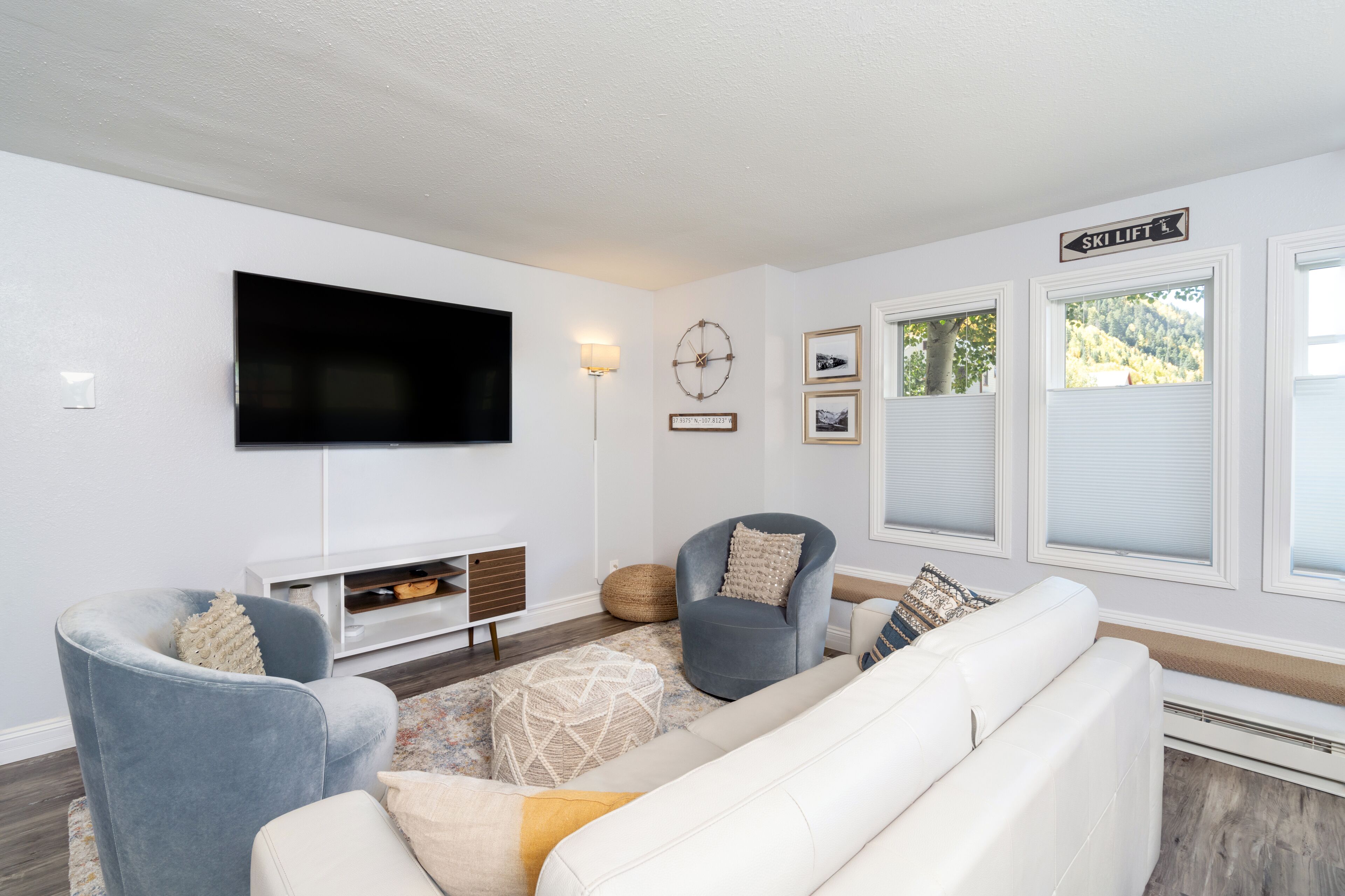 A modern living room with a flat-screen TV, a fireplace, and a ski lift sign on the wall.