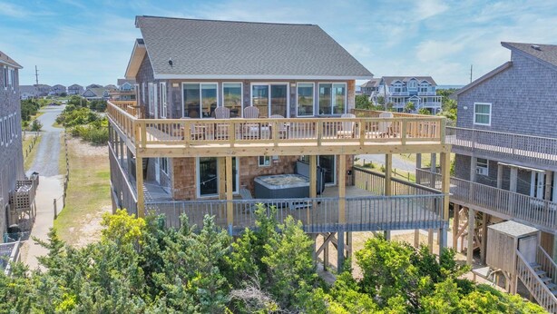 Une maison à deux étages dotée d’un balcon, d’un jacuzzi et offrant une vue sur les maisons voisines.