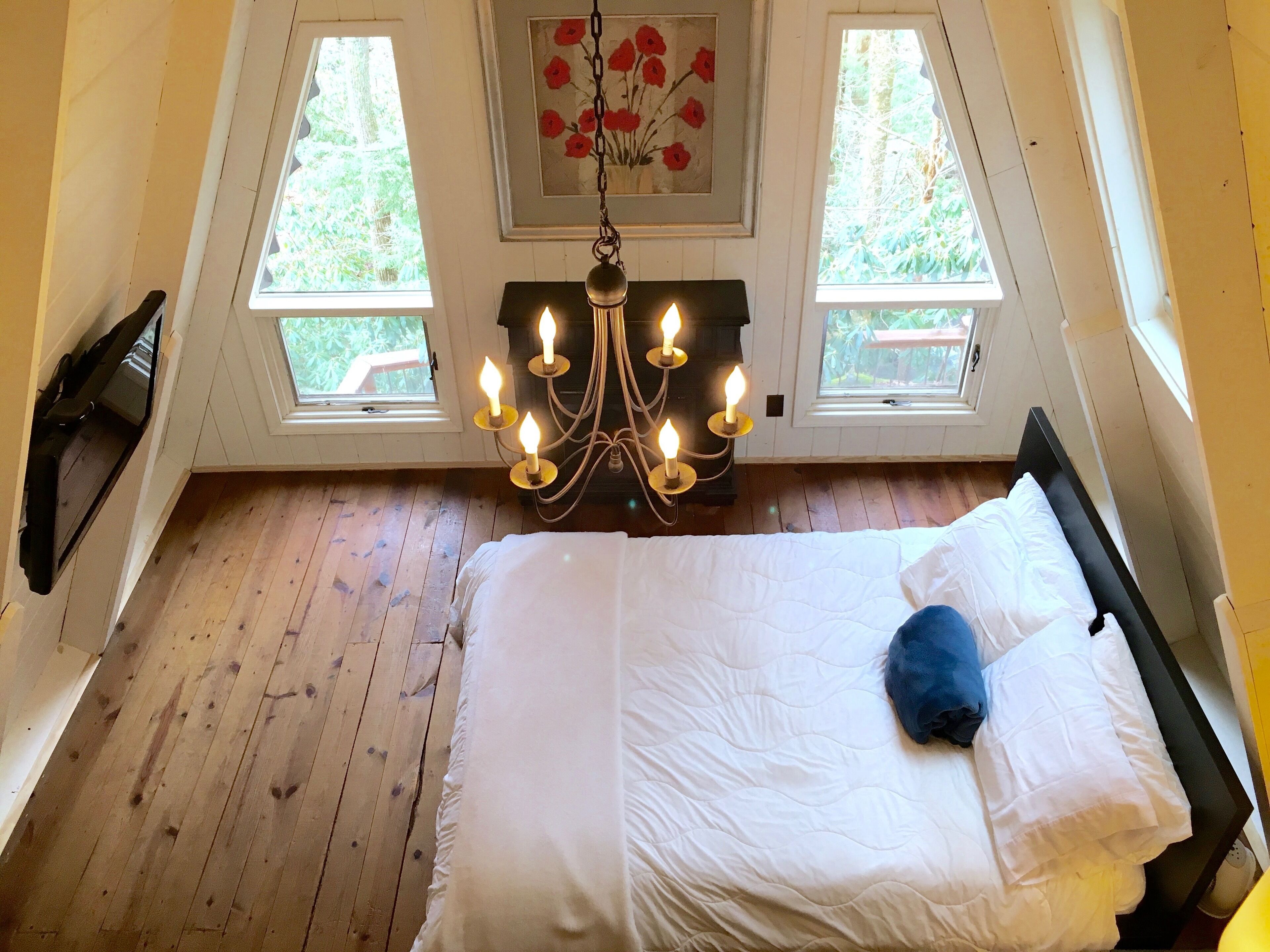 Ein Schlafzimmer mit einem Bett, einer Chandelier und zwei Fenstern.