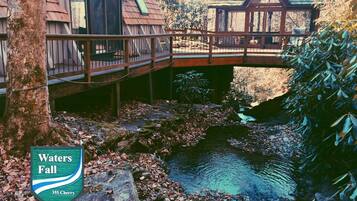 A wooden bridge over a small stream with a sign reading "Waters Fall 355 Cherry."