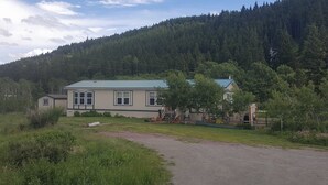 Ein zweistöckiges Haus mit blauem Dach, umgeben von einem bewaldeten Hang.