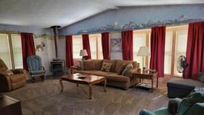 Ein gemütliches Wohnzimmer mit Kamin, einer Couch, einem Sessel und einem Ventilator.