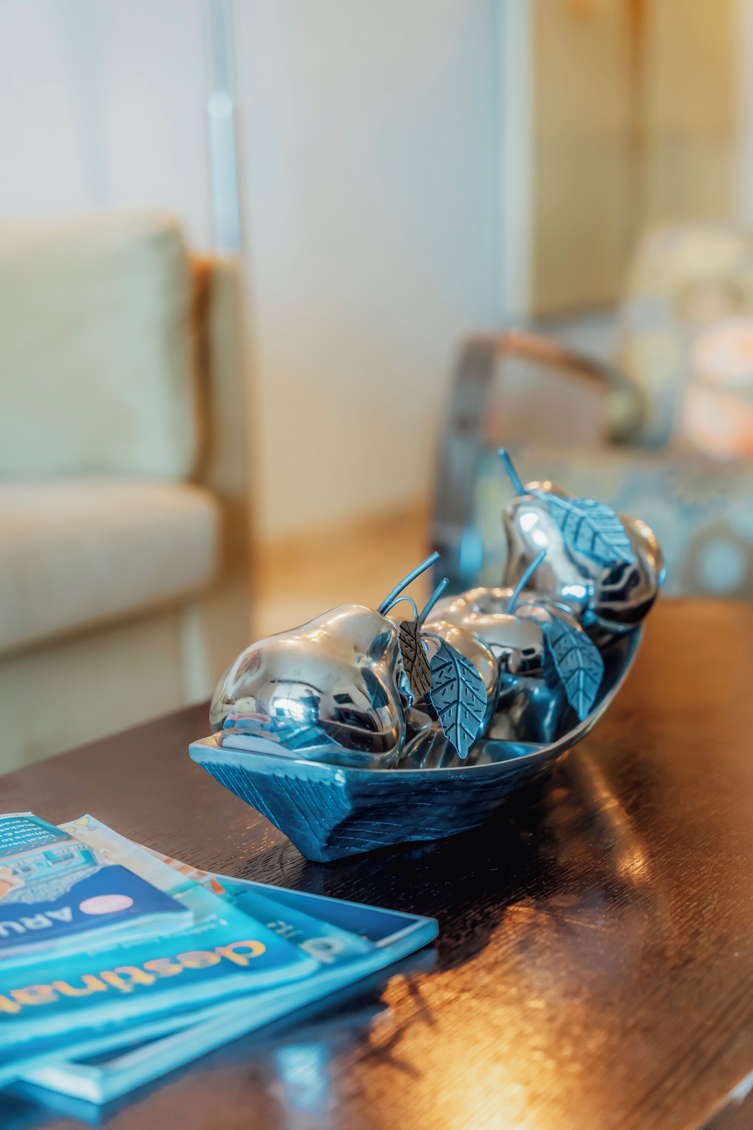 A decorative glass bowl with silverware and leaves on a wooden table.