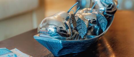 A decorative glass bowl with silverware and leaves on a wooden table.