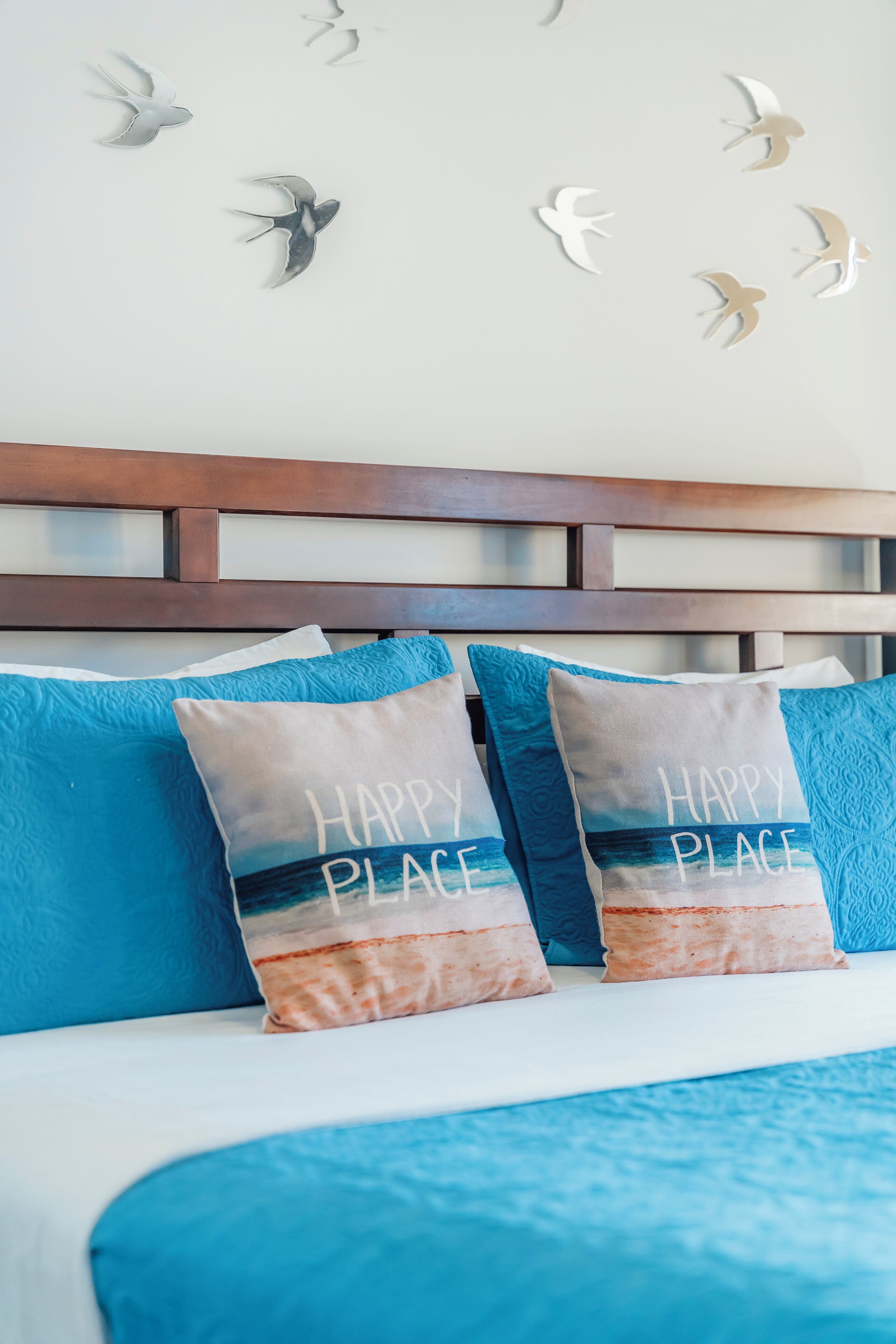 Una cama con ropa de cama y almohadas que dicen "HAPPY PLACE".