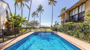 A swimming pool with a turtle, surrounded by palm trees and a view of the ocean.