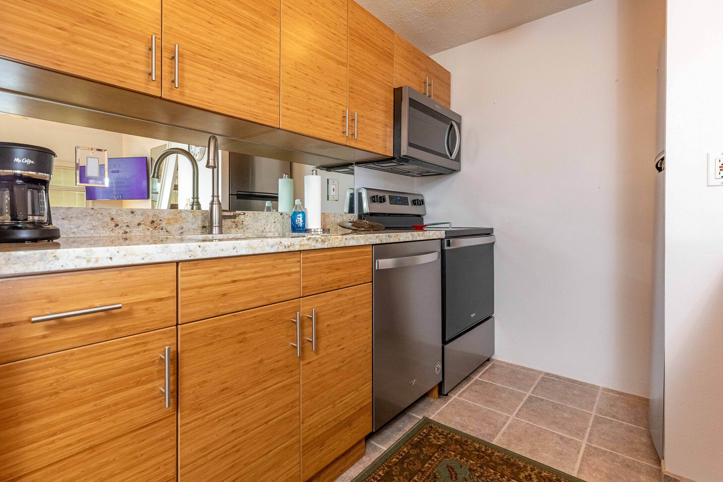 A kitchen with wooden cabinets, stainless steel appliances, a coffee maker, and a microwave.