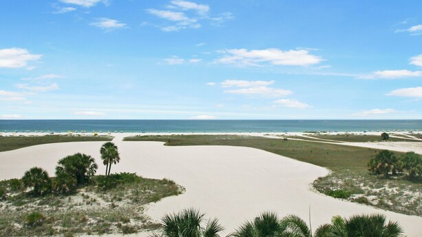 A beach with sand dunes, palm trees, and a clear view of the ocean. - Surf Beach 502 - Spectacular Sunsets - Beach Front (Treasure Island)