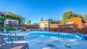 A backyard with a swimming pool, lounge chairs, and a wooden fence. - Cozy condo in Steamboat Springs.  Close to slopes! (Steamboat Springs)
