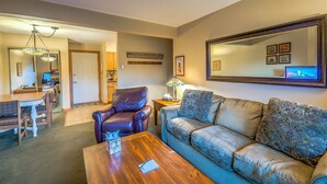 A living room with a sofa, a coffee table, a leather chair, a dining table with chairs, a lamp, and a television. - Cozy condo in Steamboat Springs.  Close to slopes! (Steamboat Springs)